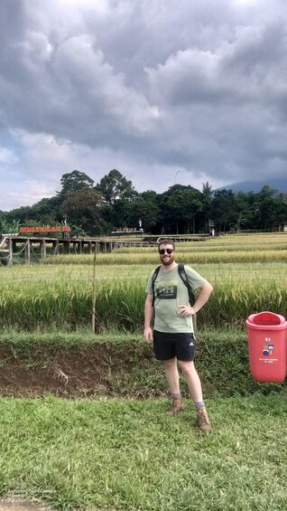 A person standing in a rice field with a cloudy sky in the background. 3