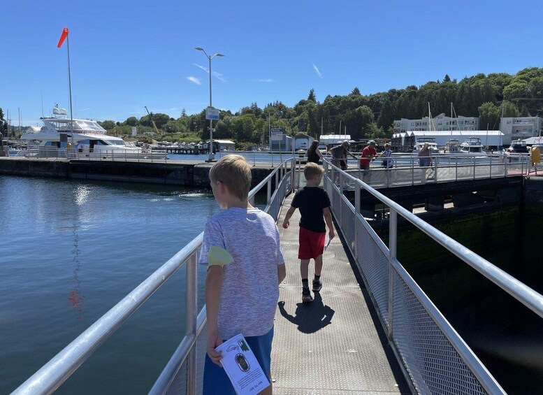 A pier with people walking, a boat docked, and a flag on a pole. 4