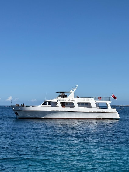 A white yacht with a flag on the stern, sailing on a calm sea. 4