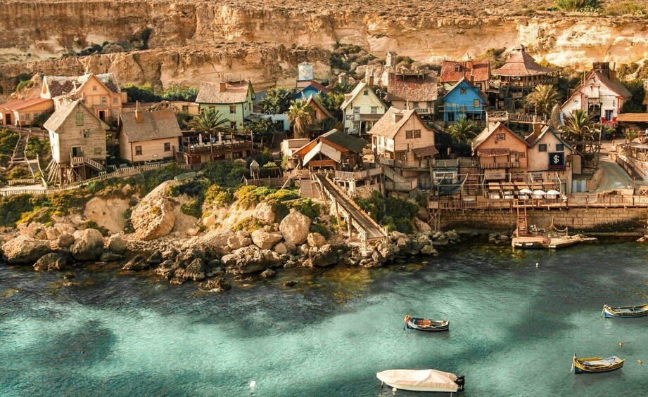 A coastal village with colorful houses, a rocky shoreline, and boats in the water. 5