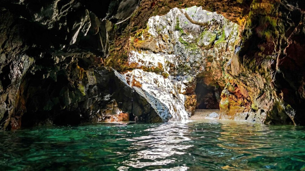A cave with a waterfall and clear water. 3