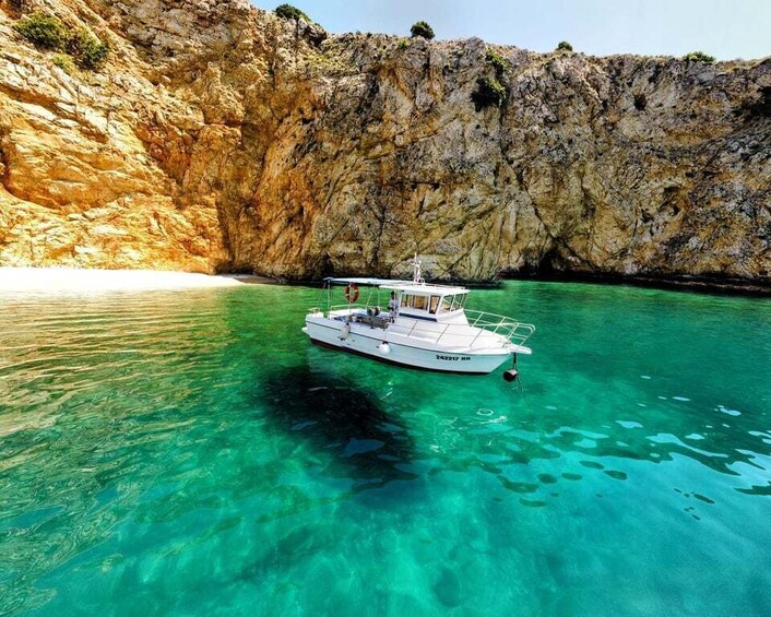 A boat anchored near a rocky cliff with clear turquoise water. 1