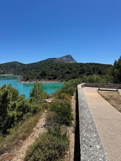 A coastal landscape with a turquoise lake, a mountain in the background, and a paved walkway. 4