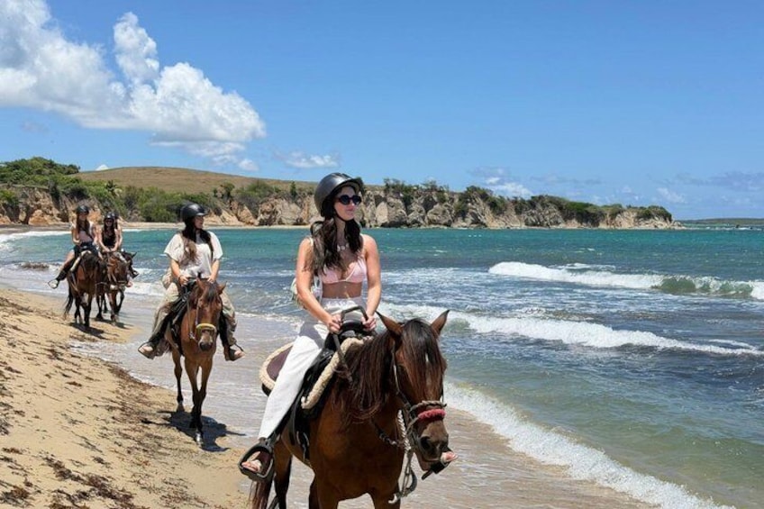 A beach with people riding horses along the shore. 1