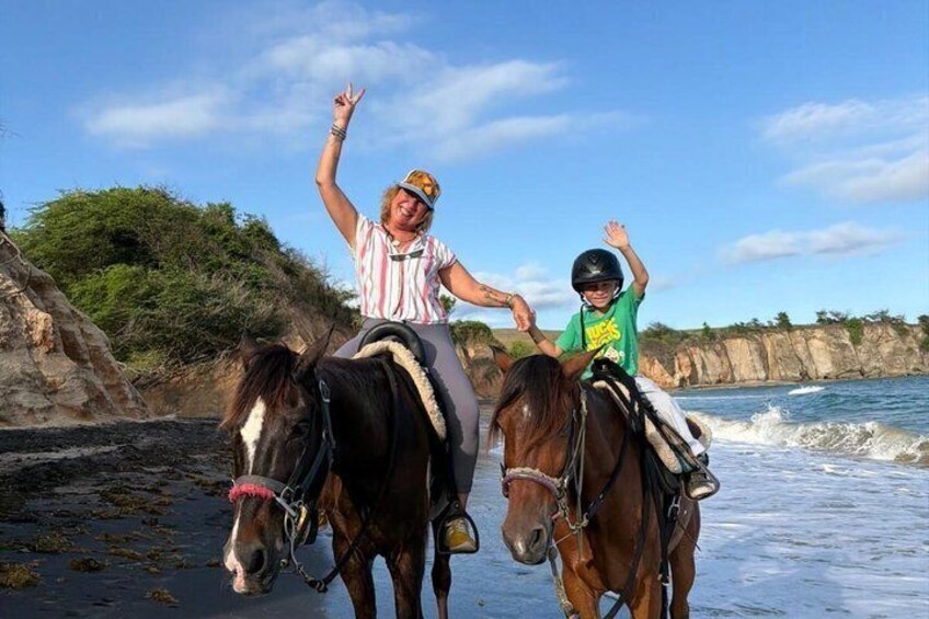 Two people riding horses on a beach with waves in the background. 3