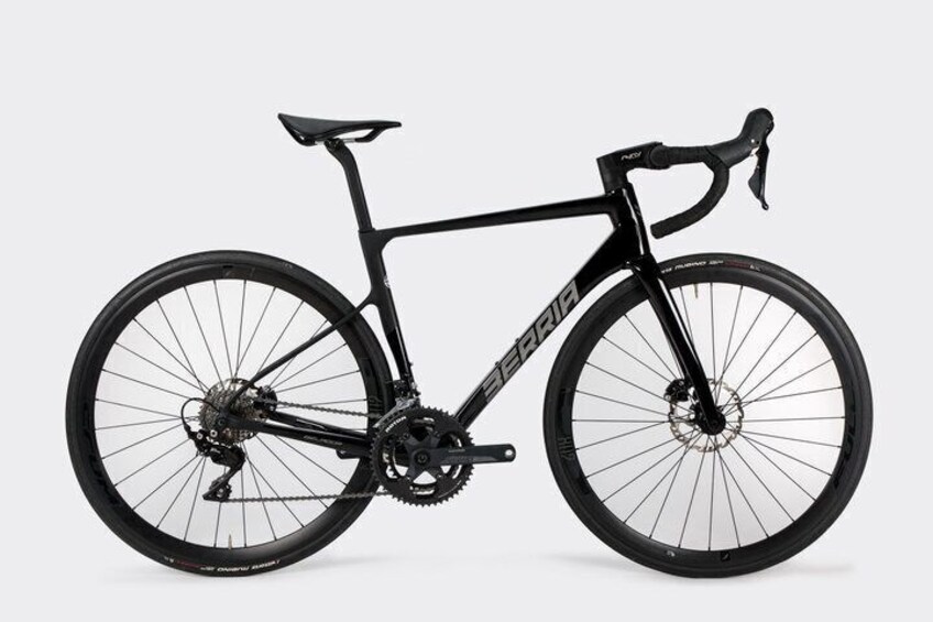 A black road bike with a front suspension fork, a gear system, and a saddle. 2