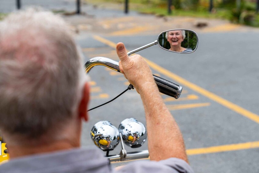 A person riding a motorcycle with a side mirror reflecting a person. 3