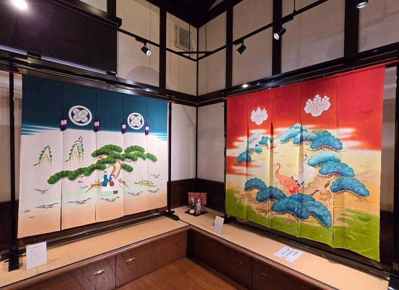 Traditional Japanese artwork displayed in a gallery with a wooden floor and black-framed windows. 5