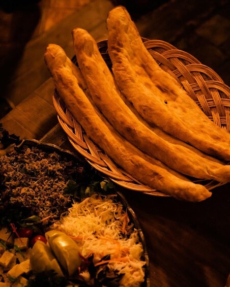 A basket of breadsticks and a dish with shredded cheese and vegetables. 5