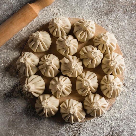A wooden board with dumplings arranged in a circular pattern. 4