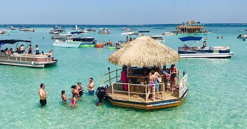 A tropical island with clear turquoise waters, a thatched-roof boat with people on it, and several other boats in the background. 2
