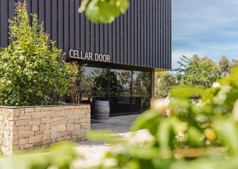 A modern building with a sign reading 'CELLAR DOOR' and a stone wall in the foreground. 4