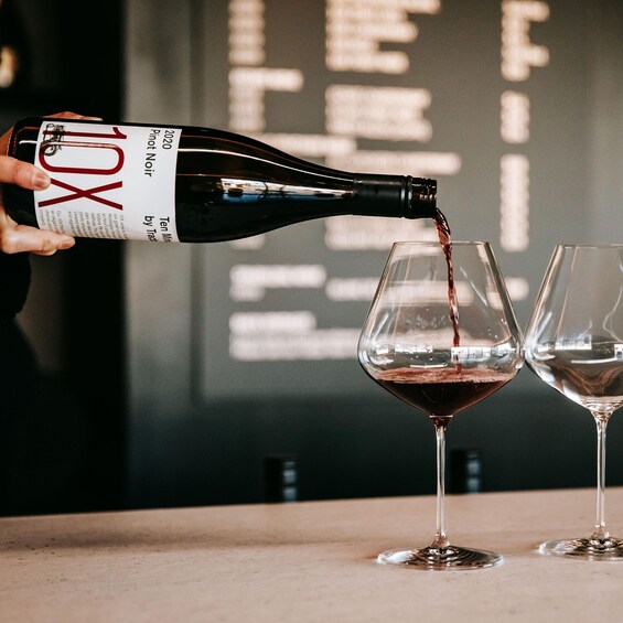 A bottle of Pinot Noir being poured into a wine glass. 2