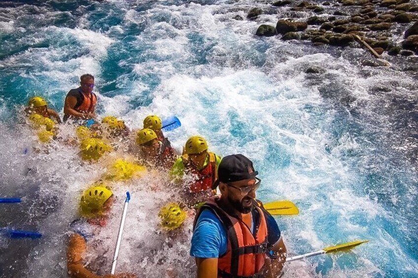 A group of people rafting on a river with white water rapids. 1