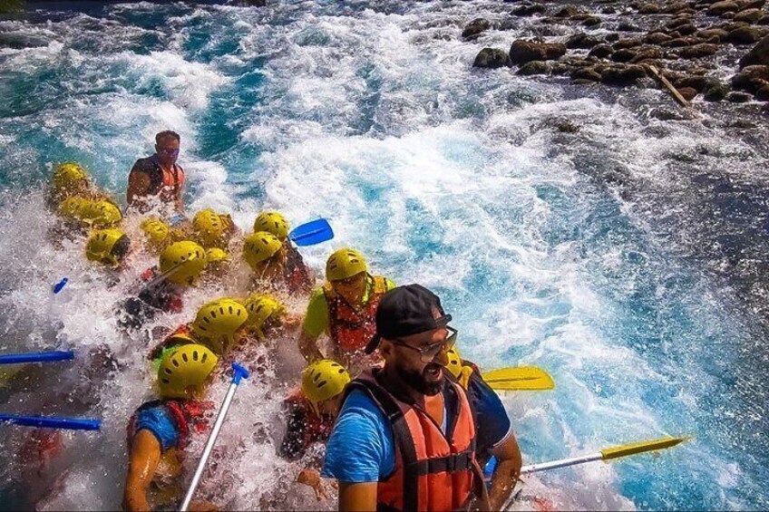 A group of people in a raft navigating through a river with rapids. 5