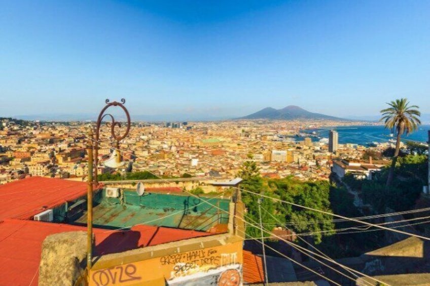 A cityscape with a mountain in the background, a red-roofed building in the foreground, and a palm tree. 1