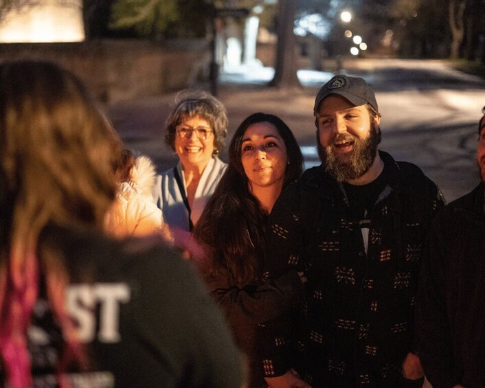 A group of people standing outdoors at night. 2