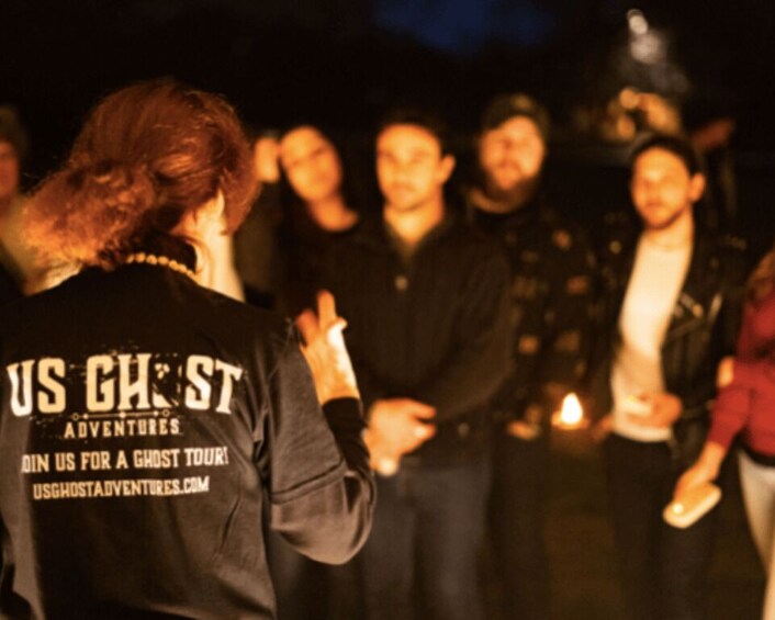 A group of people at a nighttime event, some wearing a jacket with 'US GHOST ADVENTURES' text. 5