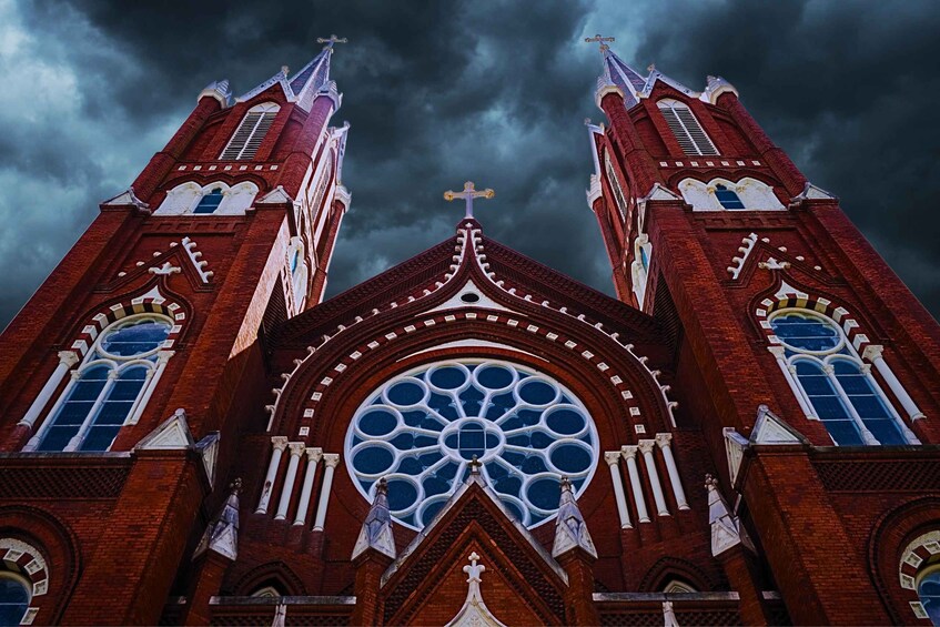 A Gothic-style church with twin towers, a large rose window, and a cross at the top. 1