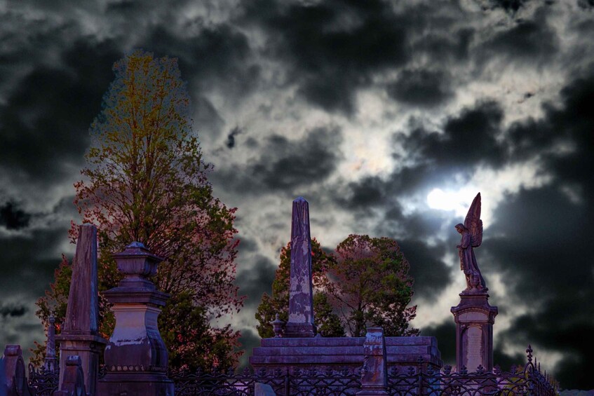 A cemetery with gravestones and a statue under a cloudy sky. 3