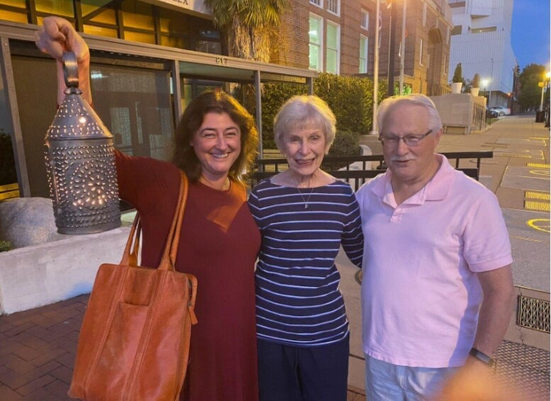 Three people standing on a sidewalk with a building in the background. 5