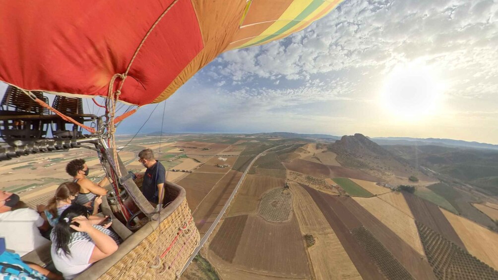 A hot air balloon with passengers over a rural landscape. 3