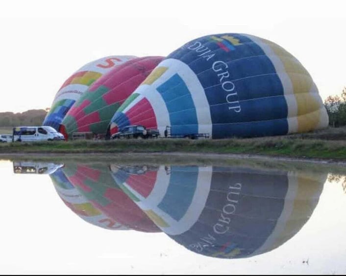 Hot air balloons with 'DIA GROUP' written on them, parked near a body of water. 5