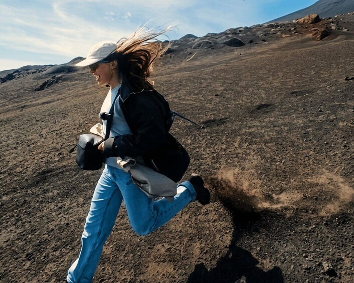 A person running on a barren landscape with rocky terrain and sparse vegetation. 1
