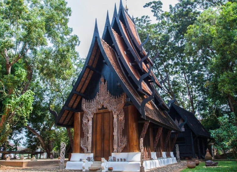 A traditional Thai temple with ornate architecture and a lush green backdrop. 5