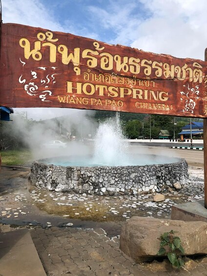 A hot spring with a stone wall and a sign in a foreign language. 4