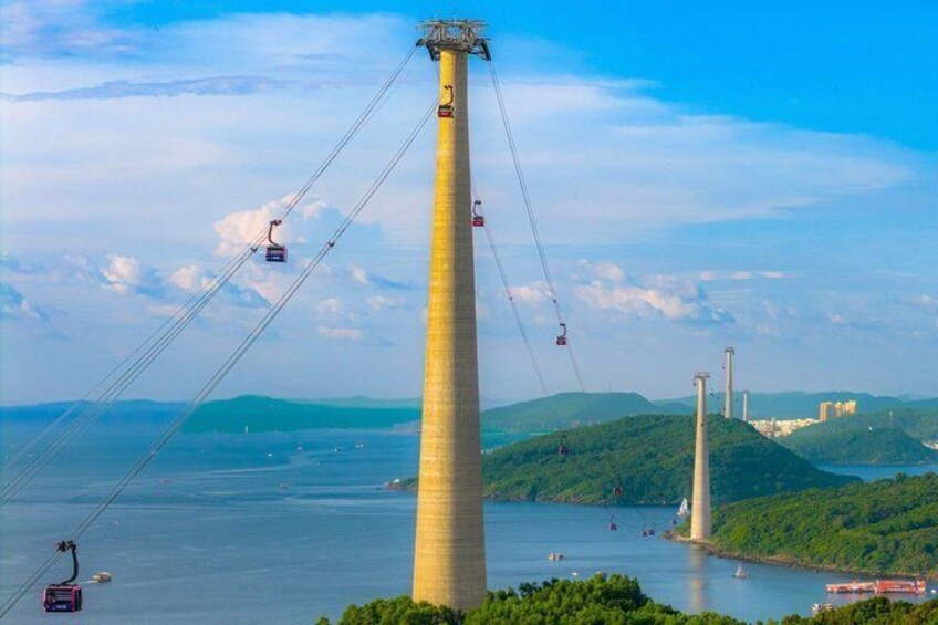 A tall tower with a cable car system, a bridge, and a body of water. 1