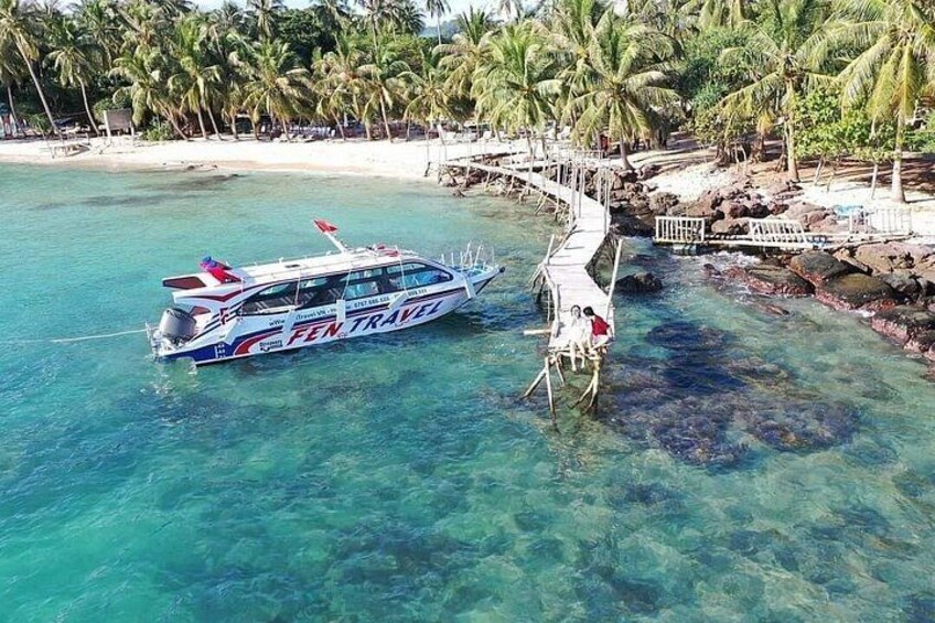 A boat named 'FEN TRAVEL' docked at a pier with a beach and palm trees in the background. 5