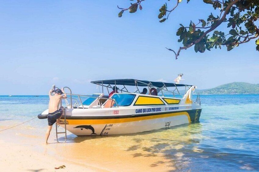 A boat named 'CANO DU LICH PHU 0000' on a sandy beach with clear blue water and a distant green hill. 3