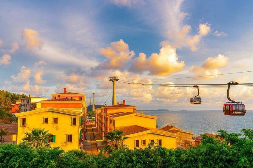 A coastal town with yellow buildings, a cable car system, and a body of water in the background. 4