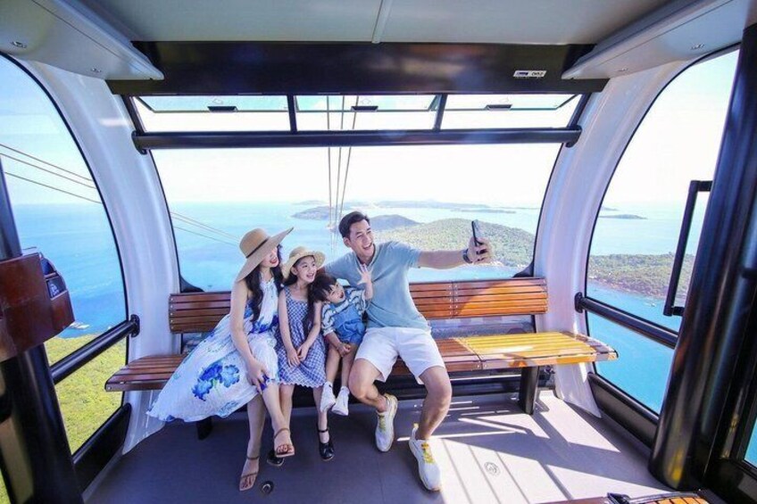 A family on a cable car with a scenic view of the ocean and hills. 5