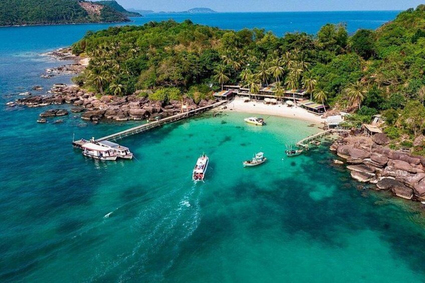 A tropical island with clear turquoise waters, a dock, and a small boat. 5
