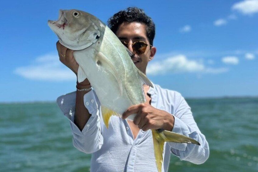 A person holding a large fish by the ocean. 2