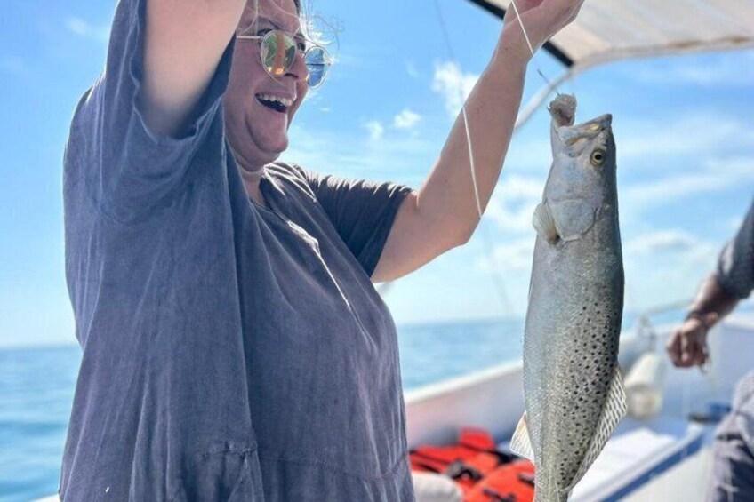 A person holding a fish on a boat. 3