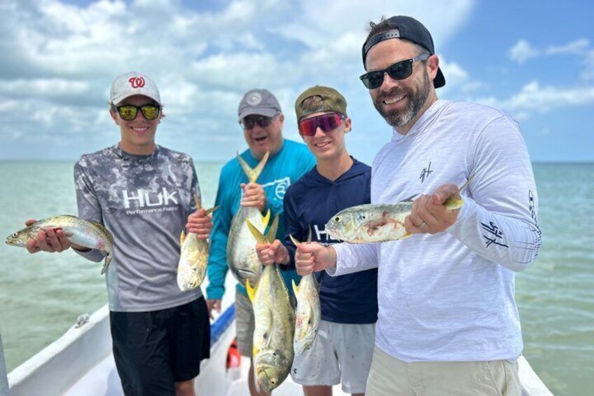 Four people on a boat holding fish. 1