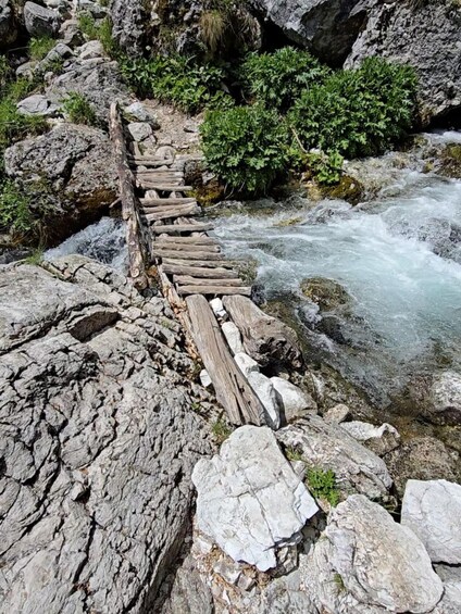 A rocky riverbank with a wooden bridge. 5