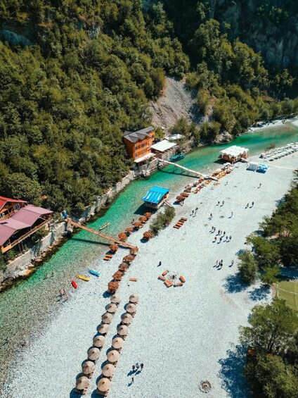 A coastal resort with a beach, umbrellas, and a pier extending into turquoise waters. 4