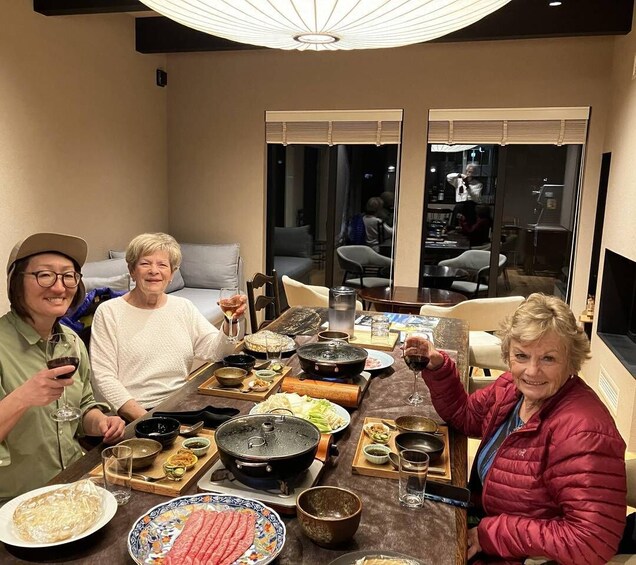 Three people dining at a table with various dishes, including a hot pot and sashimi. 2
