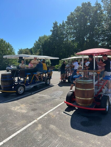 A group of people on a wooden cart with barrels, driving on a paved road. 3