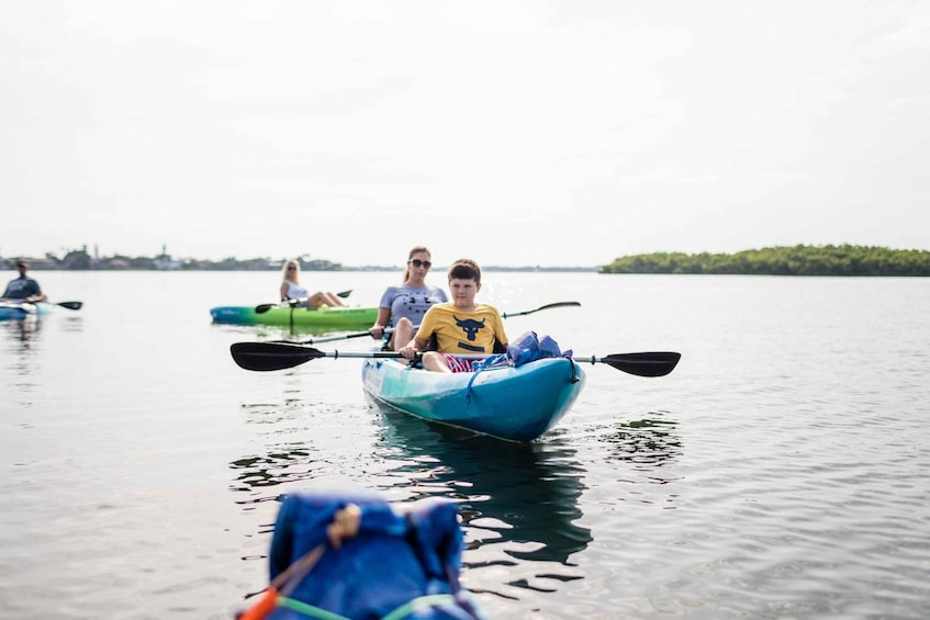 A group of people kayaking on a calm lake with a distant shoreline. 5