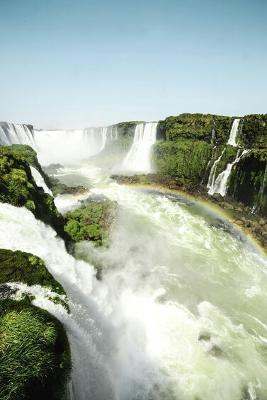 A large waterfall with a rainbow, surrounded by lush greenery. 3