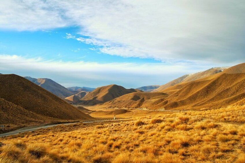 A mountainous landscape with a road and dry grass. 3