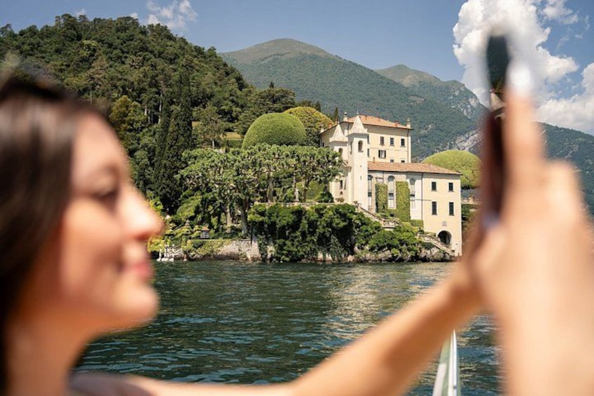 A person taking a photo of a lake with a building on the shore. 4