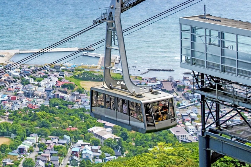 A cable car system over a coastal town with a clear view of the sea and residential buildings below. 1