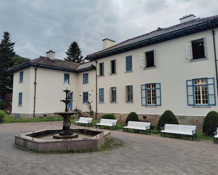 A courtyard with a fountain, benches, and a building with blue shutters. 4