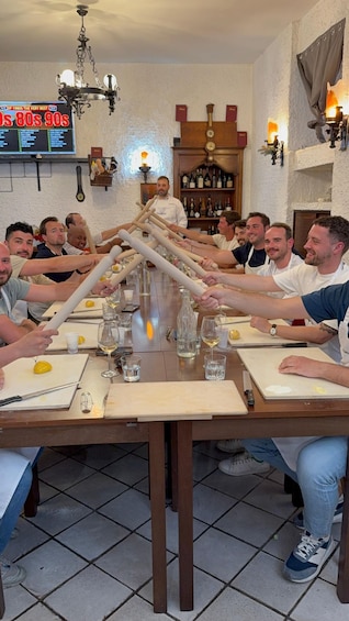A group of people participating in a dough stretching activity at a restaurant. 1